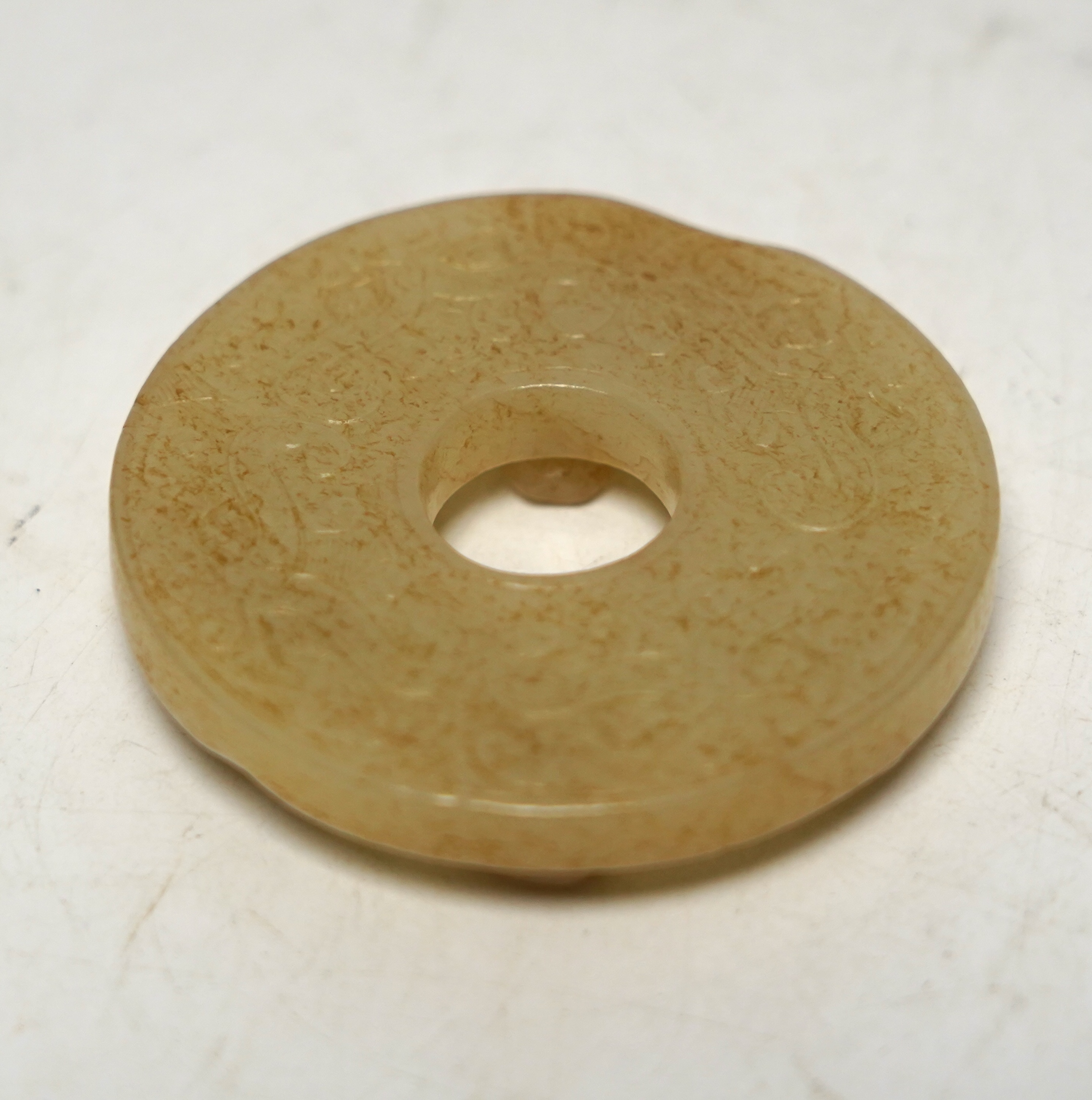 An 18th century Chinese mottled jade bi disc, decorated with two carved chilong, 5.8cm diameter